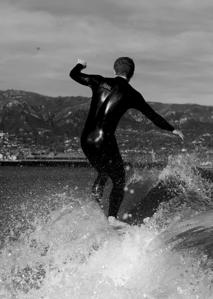 Surfer in a wetsuit riding a wave, black and white